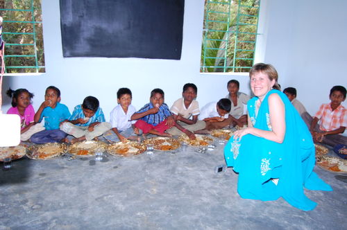 Gill with kids in a classroom eating goat curry.
