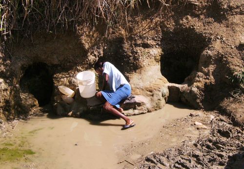 A woman sieving muddy water to make it drinkable