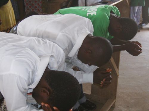 3 young men praying at the conference.